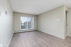 This room features light-colored plank flooring, neutral wall paint, and a large window with vertical blinds - 