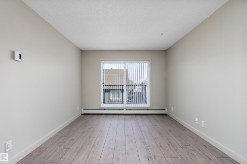 This room features light-colored walls, hardwood flooring, and a window with vertical blinds - 309 4008 Savaryn Drive, Edmonton, AB - Indoor Photo Showing Other Room