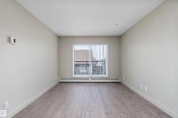 This room features light-colored walls, hardwood flooring, and a window with vertical blinds - 
