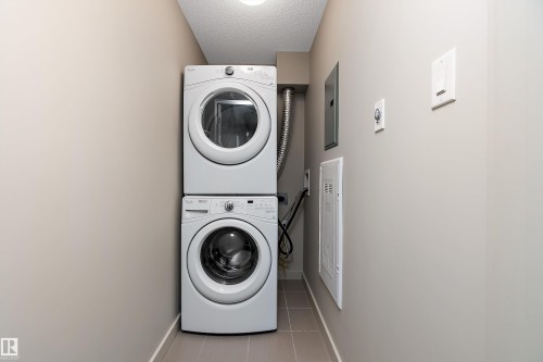 Dedicated laundry area featuring a white stacked washer and dryer unit - 309 4008 Savaryn Drive, Edmonton, AB - Indoor Photo Showing Laundry Room