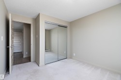 This room features neutral-toned walls, light-colored carpeting, and mirrored sliding closet doors - 
