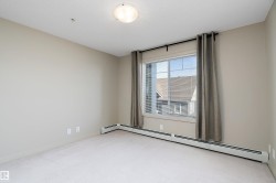 This room features neutral-toned walls, a window with blinds and curtains, and baseboard heating - 