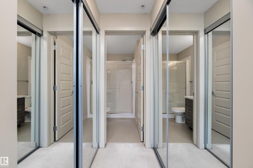 This hallway features mirrored sliding closet doors and light-colored walls - 309 4008 Savaryn Drive, Edmonton, AB -  With Balcony With Exterior