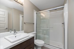 Bathroom featuring a dark wood vanity with a white countertop and rectangular sink, an overhead vanity light, and a glass-enclosed shower - 
