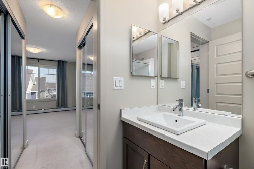 This hallway features mirrored closet doors and leads to a room with a window providing exterior views - 309 4008 Savaryn Drive, Edmonton, AB - Indoor Photo Showing Bathroom
