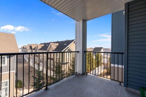 The property features a balcony with a black metal railing, concrete flooring, and an overhead soffit - 309 4008 Savaryn Drive, Edmonton, AB - Outdoor With Balcony With Exterior