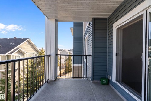 The property features a private balcony with a durable concrete floor, black metal railings, and a sliding glass door for access - 309 4008 Savaryn Drive, Edmonton, AB - Outdoor With Balcony With Exterior