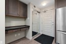 Entryway featuring wood plank flooring, a built-in desk with drawers, overhead cabinetry, and a full-length mirrored closet - 309 4008 Savaryn Drive, Edmonton, AB  - Indoor 