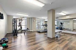 Fitness area featuring wood-look flooring, large windows, recessed lighting, and a mirrored wall - 