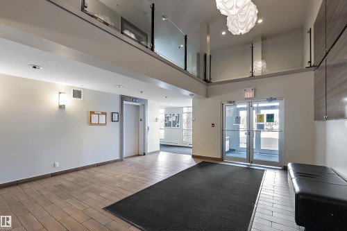 Lobby area featuring tiled flooring, a modern light fixture, and an elevator - 309 4008 Savaryn Drive, Edmonton, AB - Indoor Photo Showing Other Room