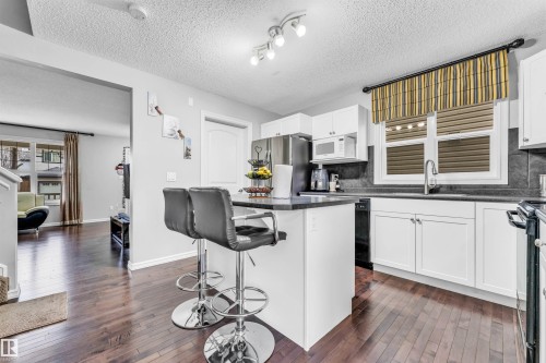 The kitchen features white cabinetry, dark countertops, and stainless steel appliances - 607 Allard Boulevard, Edmonton, AB - Indoor Photo Showing Kitchen