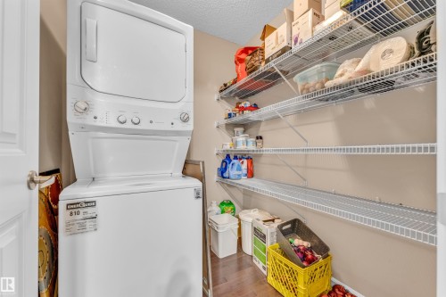 Laundry area with a white stacked washer and dryer, complemented by built-in wire shelving - 607 Allard Boulevard, Edmonton, AB - Indoor Photo Showing Laundry Room