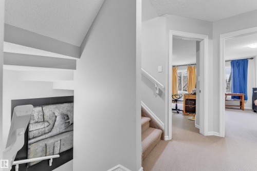 The property features a staircase with light-colored carpeting and white handrails, leading to a landing with a consistent light-colored carpet - 607 Allard Boulevard, Edmonton, AB - Indoor