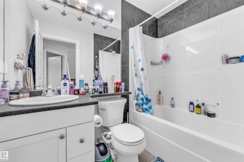The bathroom features a vanity with a sink, a toilet, and a bathtub with a shower - 607 Allard Boulevard, Edmonton, AB - Indoor Photo Showing Bathroom
