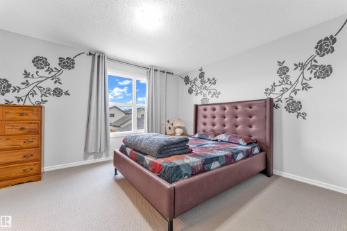 This room features a window providing natural light, light-colored carpeting, and decorative wall accents - 607 Allard Boulevard, Edmonton, AB - Indoor Photo Showing Bedroom
