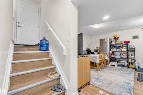 Inviting living space featuring a stairway with light-toned wood treads and white risers, a white handrail, and a white door at the top of the stairs - 607 Allard Boulevard, Edmonton, AB - Indoor Photo Showing Other Room