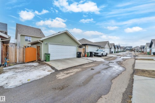 The property features a private garage with a concrete driveway and a fenced yard with a wooden gate - 607 Allard Boulevard, Edmonton, AB - Outdoor
