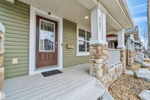 The property features an inviting front porch with stone accents, a durable siding exterior, and a brown entry door with windowpanes - 607 Allard Boulevard, Edmonton, AB - Outdoor With Exterior
