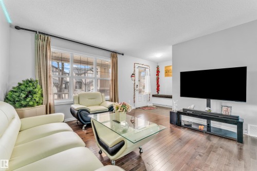 Spacious living area featuring rich hardwood floors, a large window providing natural light, and light-colored walls - 607 Allard Boulevard, Edmonton, AB - Indoor Photo Showing Living Room