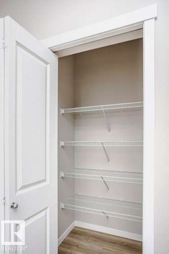 This property offers practical storage solutions, featuring an interior closet with wire shelving and durable flooring - 99 320 Secord Boulevard, Edmonton, AB - Indoor With Storage