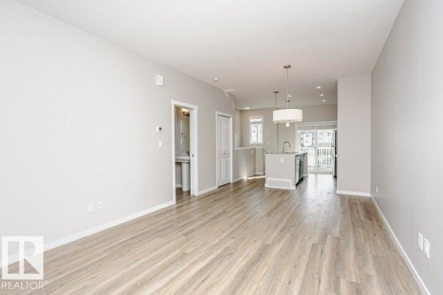 Open concept living area featuring light-toned flooring and neutral walls - 99 320 Secord Boulevard, Edmonton, AB - Indoor Photo Showing Other Room