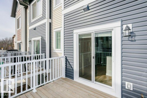 The property features a deck with white railings and a sliding glass door, providing access to the interior - 99 320 Secord Boulevard, Edmonton, AB - Outdoor With Exterior