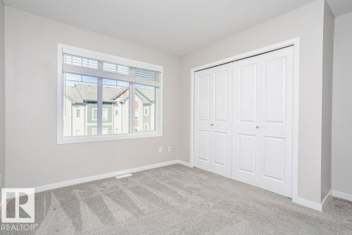 This room features light grey walls and grey carpet flooring - 99 320 Secord Boulevard, Edmonton, AB - Indoor Photo Showing Other Room