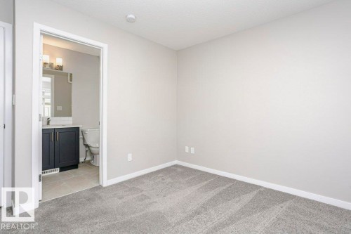 This room features light grey walls and grey carpet flooring - 99 320 Secord Boulevard, Edmonton, AB - Indoor Photo Showing Other Room