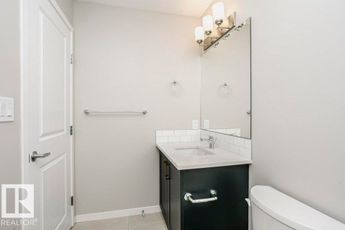 Bathroom featuring a vanity with a light-colored countertop, a rectangular sink, and a mirrored wall cabinet with overhead lighting - 99 320 Secord Boulevard, Edmonton, AB - Indoor Photo Showing Bathroom