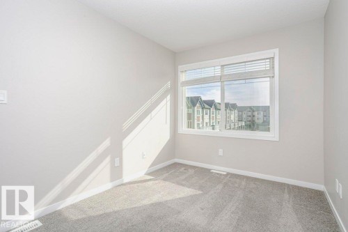 The room features light gray carpeting and white walls, creating a neutral and inviting atmosphere - 99 320 Secord Boulevard, Edmonton, AB - Indoor Photo Showing Other Room