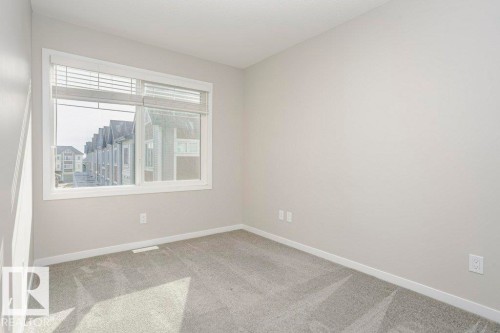 Bright room featuring a window with blinds, light-colored walls, and carpeting - 99 320 Secord Boulevard, Edmonton, AB - Indoor Photo Showing Other Room