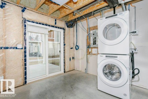 The property includes a sliding glass patio door, a concrete floor, and exposed ceiling joists - 99 320 Secord Boulevard, Edmonton, AB - Indoor Photo Showing Laundry Room