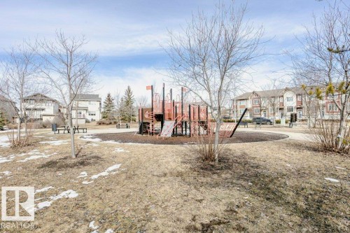 The property is situated within a community featuring a park with a playground structure and surrounding residential buildings - 99 320 Secord Boulevard, Edmonton, AB - Outdoor