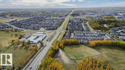 Aerial view showcasing the surrounding residential area, featuring properties with gray roofs and a prominent road - 99 320 Secord Boulevard, Edmonton, AB - Outdoor With View