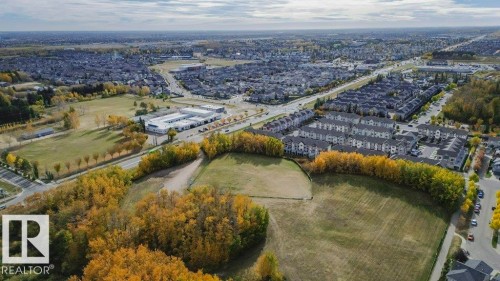 Expansive aerial view showcasing the surrounding residential area and abundant green spaces - 99 320 Secord Boulevard, Edmonton, AB - Outdoor With View