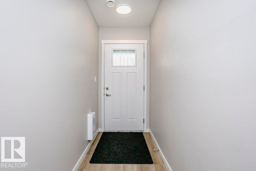 Entryway featuring light-colored walls, wood-look flooring, and a white front door with an integrated window - 99 320 Secord Boulevard, Edmonton, AB - Indoor Photo Showing Other Room