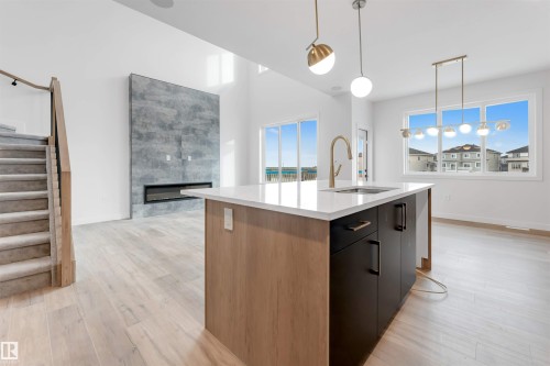 The property features a modern kitchen island with a white countertop and a gold-toned faucet - 20 Meadowgrove Landing, Spruce Grove, AB - Indoor Photo Showing Kitchen