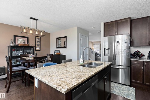 Kitchen featuring granite countertops, stainless steel appliances, dark wood cabinetry, and a double basin sink - 6822 Cardinal Link, Edmonton, AB - Indoor Photo Showing Kitchen With Double Sink