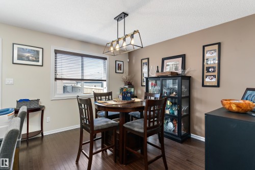 The property features rich hardwood flooring, a window with blinds, and a modern ceiling light fixture - 6822 Cardinal Link, Edmonton, AB - Indoor Photo Showing Dining Room