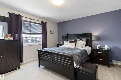 This room features a window with blinds and dark curtains, light-colored carpeting, and a ceiling light fixture - 6822 Cardinal Link, Edmonton, AB - Indoor Photo Showing Bedroom