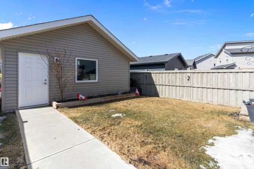 The property features a private yard with a wooden fence and a concrete walkway leading to an exterior door - 6822 Cardinal Link, Edmonton, AB - Outdoor With Exterior