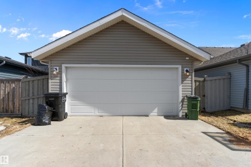 The property features an attached garage with a white garage door, gray siding, and a concrete driveway - 6822 Cardinal Link, Edmonton, AB - Outdoor With Exterior