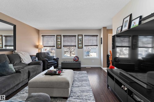 Living area featuring dark wood flooring, light-colored walls, and windows with blinds - 6822 Cardinal Link, Edmonton, AB - Indoor Photo Showing Living Room