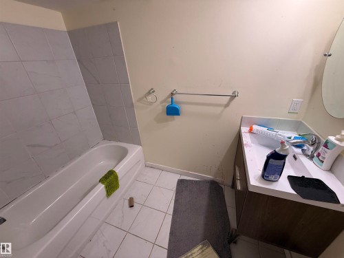 Bathroom featuring a white bathtub, tiled shower walls, and a vanity with a white countertop and base cabinet - 3317 11 Avenue, Edmonton, AB - Indoor Photo Showing Bathroom