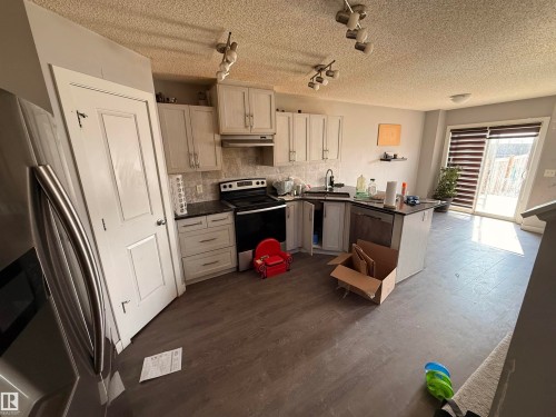 The kitchen features light-colored cabinetry, a black range, and a stainless steel refrigerator - 3317 11 Avenue, Edmonton, AB - Indoor Photo Showing Kitchen
