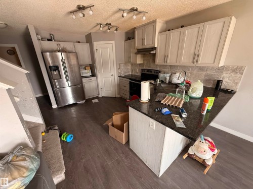 The kitchen features a stainless steel refrigerator, dark countertops, and light-toned cabinetry - 3317 11 Avenue, Edmonton, AB - Indoor Photo Showing Kitchen