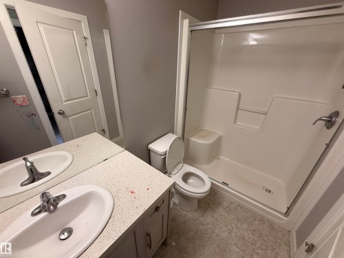 The bathroom features a vanity with two sinks, a toilet, and a stand-up shower with a glass enclosure - 3317 11 Avenue, Edmonton, AB - Indoor Photo Showing Bathroom