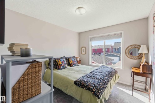 Well-lit interior space featuring a window with a view of residential rooftops, light-colored walls, and a ceiling light fixture - 4750 Crabapple Run, Edmonton, AB - Indoor Photo Showing Bedroom