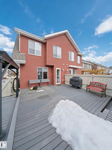This property features a composite deck, a red exterior, and a white fence - 4750 Crabapple Run, Edmonton, AB - Outdoor With Deck Patio Veranda With Exterior
