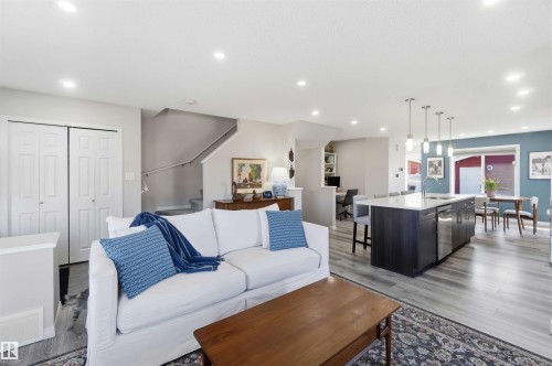 The open concept living area features recessed lighting, light-toned flooring, and a kitchen island with pendant lighting and integrated appliances - 4750 Crabapple Run, Edmonton, AB - Indoor Photo Showing Living Room